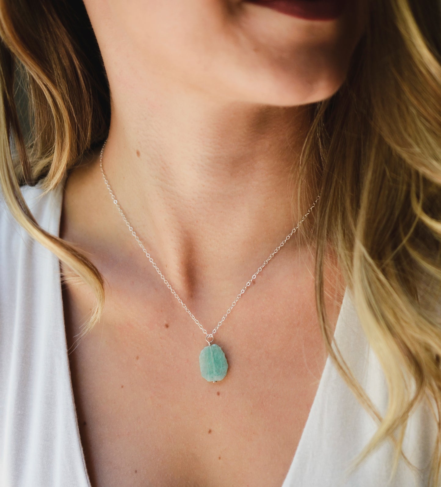 Aqua blue amazonite slice gemstone set onto a sterling silver chain. The stone is semi oval in shape, but irregular. It's smooth polished, but with raw edges.