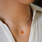 Natural orange Carnelian teardrop gemstone set onto a sterling silver chain. Modeled image.