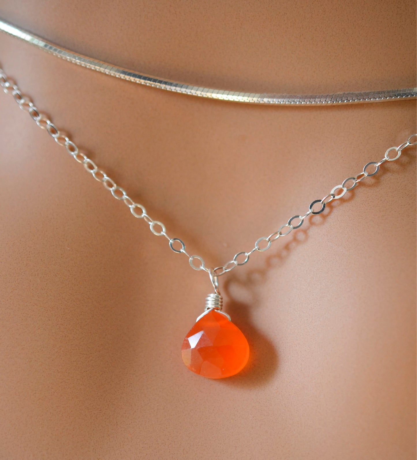 Natural orange Carnelian teardrop gemstone set onto a sterling silver chain.