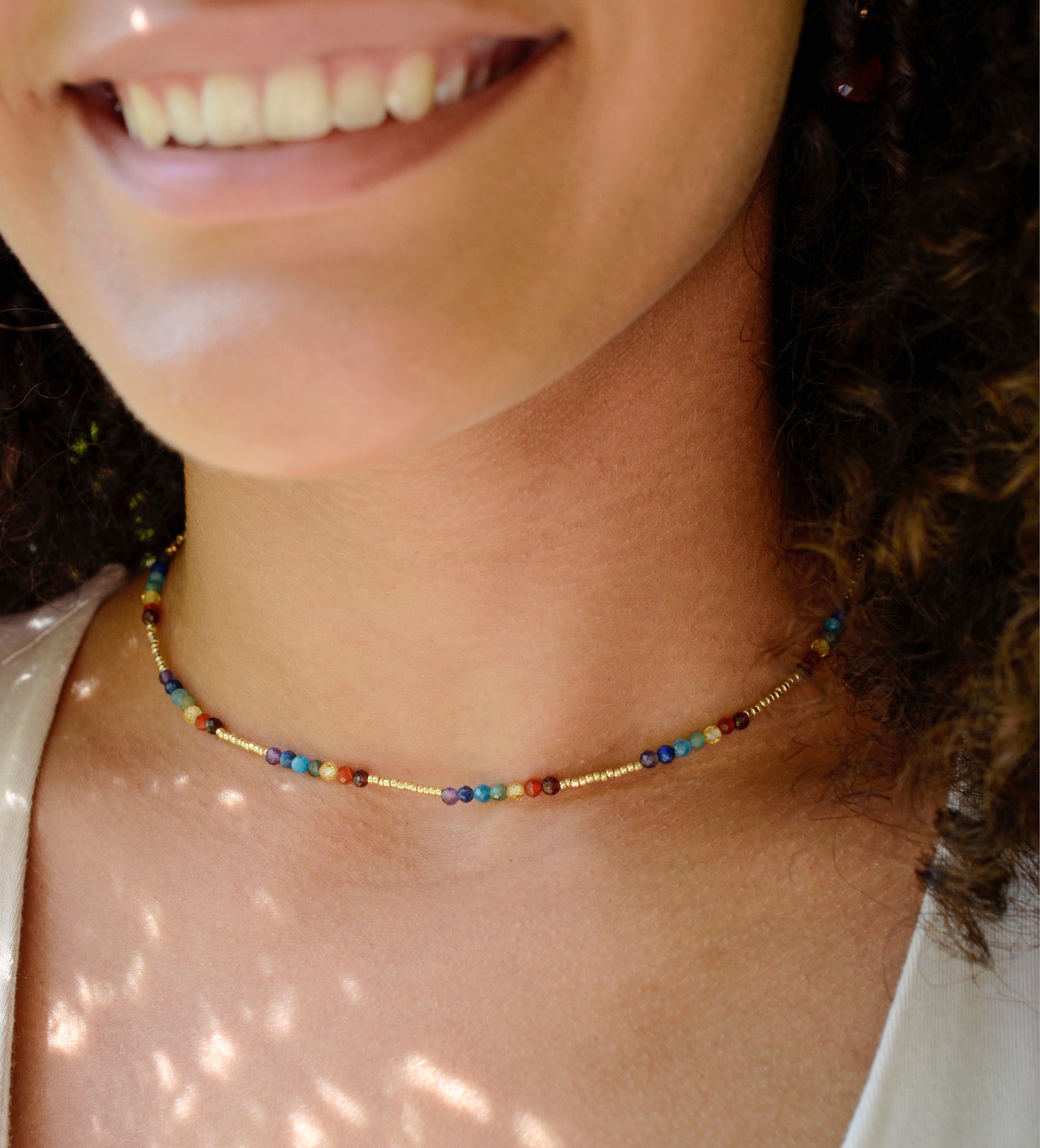Tiny stones arranged in the order of the seven chakras or rainbow colors. Colors include: purple, blue, aqua, green, yellow, orange, and red. Modeled image.