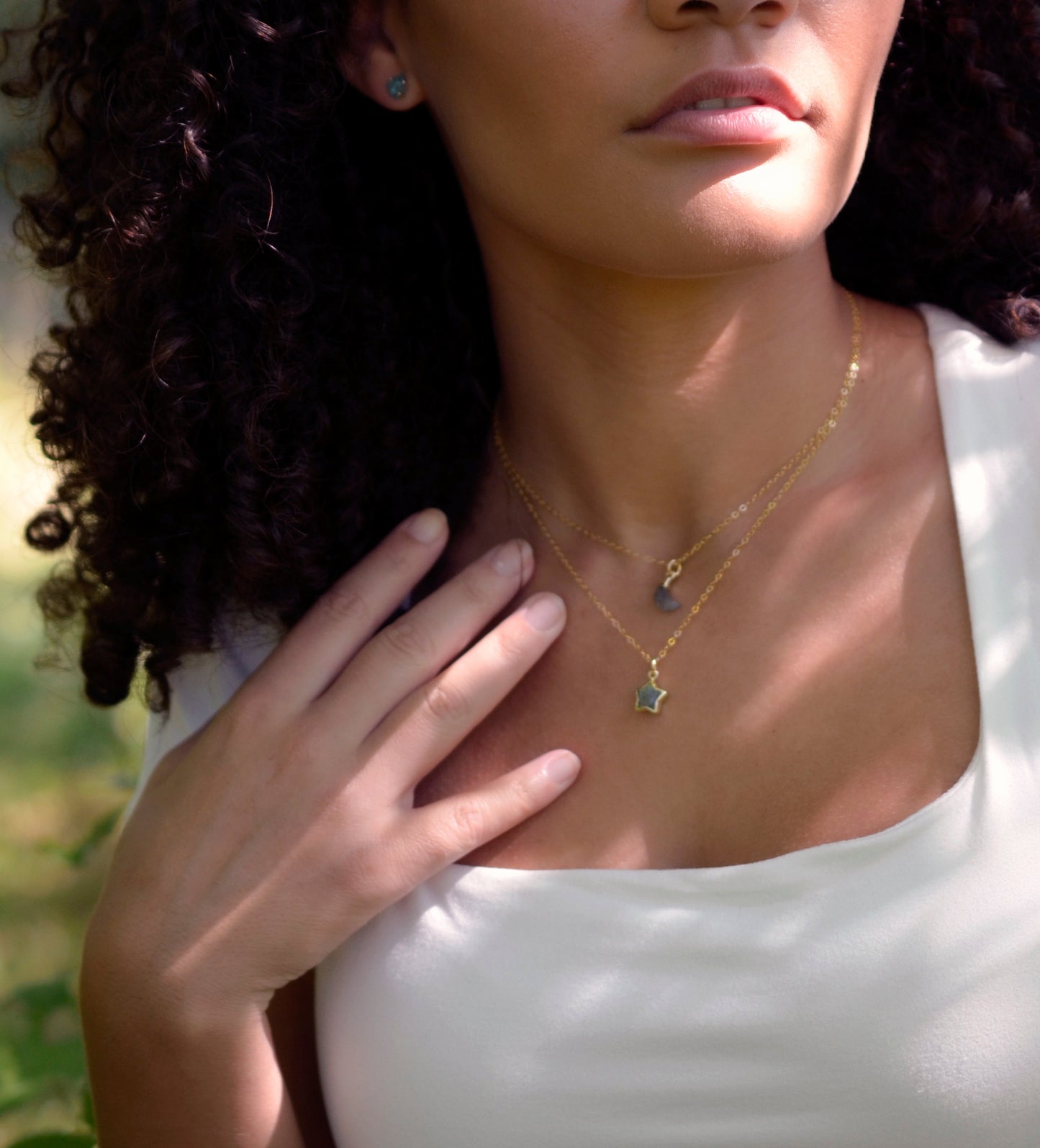 Labradorite star and moon pendants modeled on gold chains.