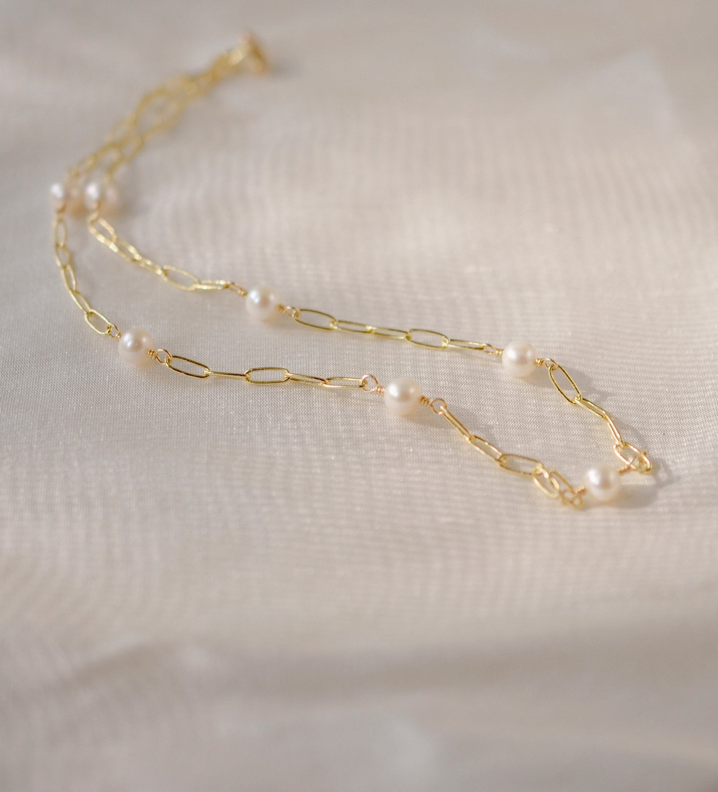 White freshwater pearls set onto a gold paperclip style chain.