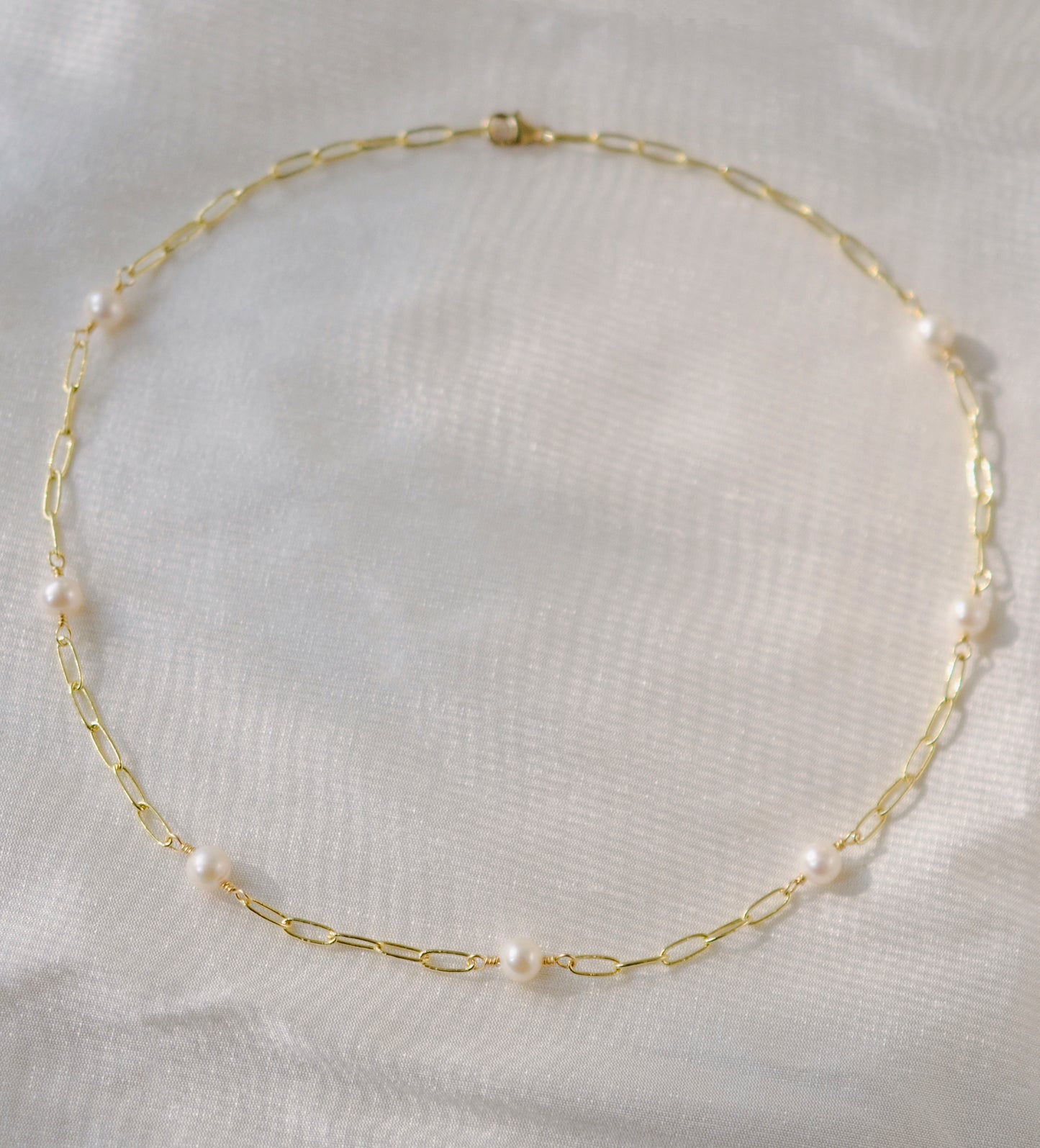 White freshwater pearls set onto a gold paperclip style chain. The paperclip style has elongated links.