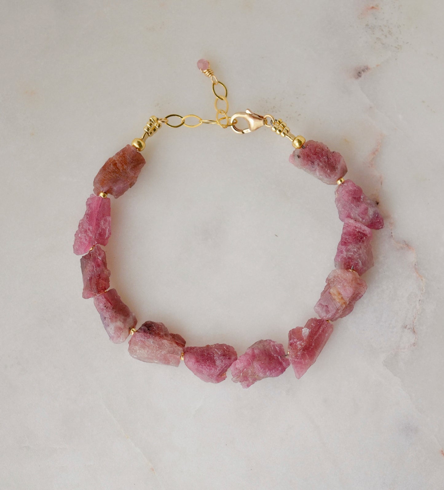 Raw pink tourmaline bracelet with tiny gold beads in-between each stone. The adjustable style is shown.