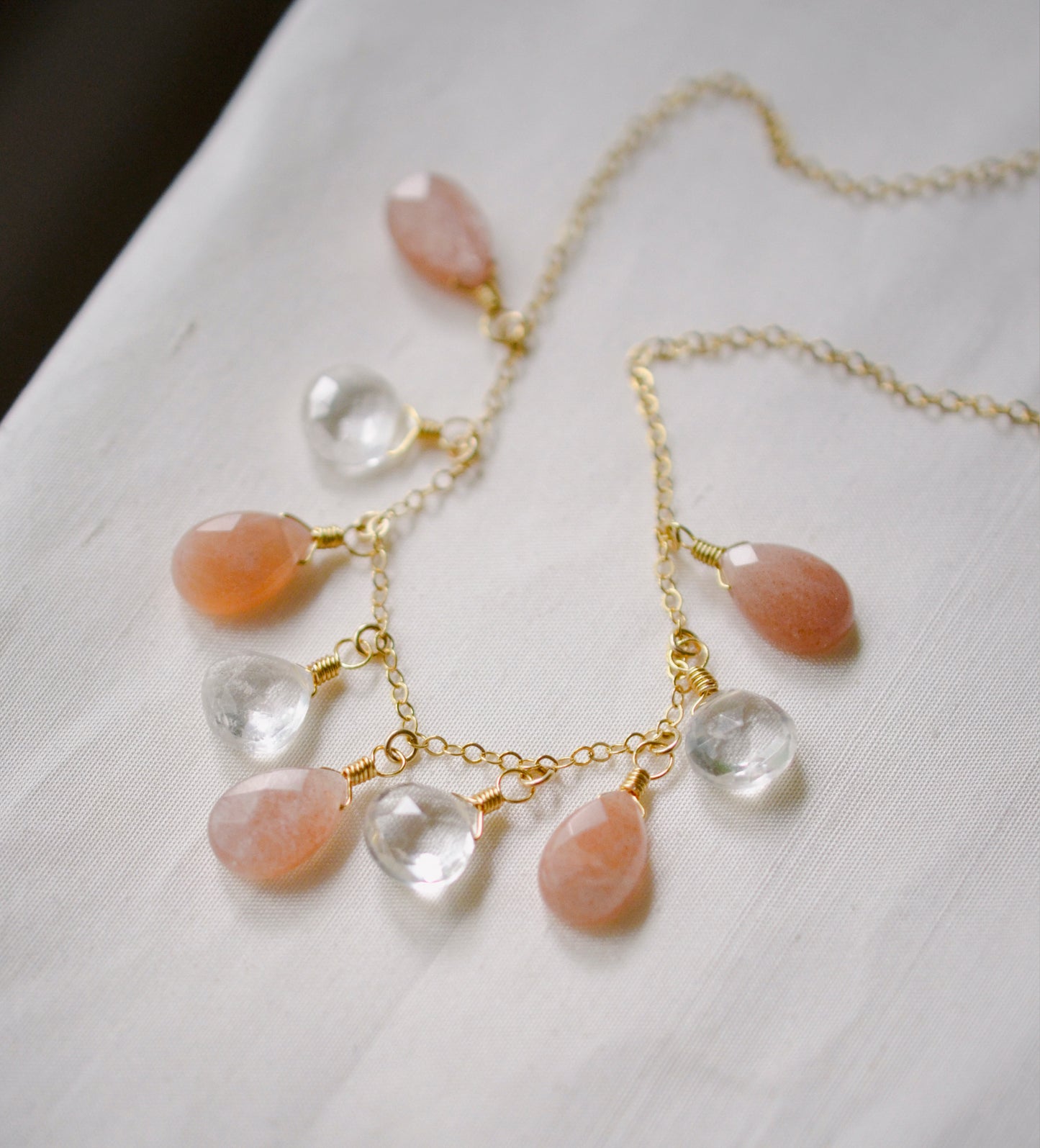 Orange, peach Sunstone and clear Crystal Quartz teardrops dangle off a 14k gold filled chain.