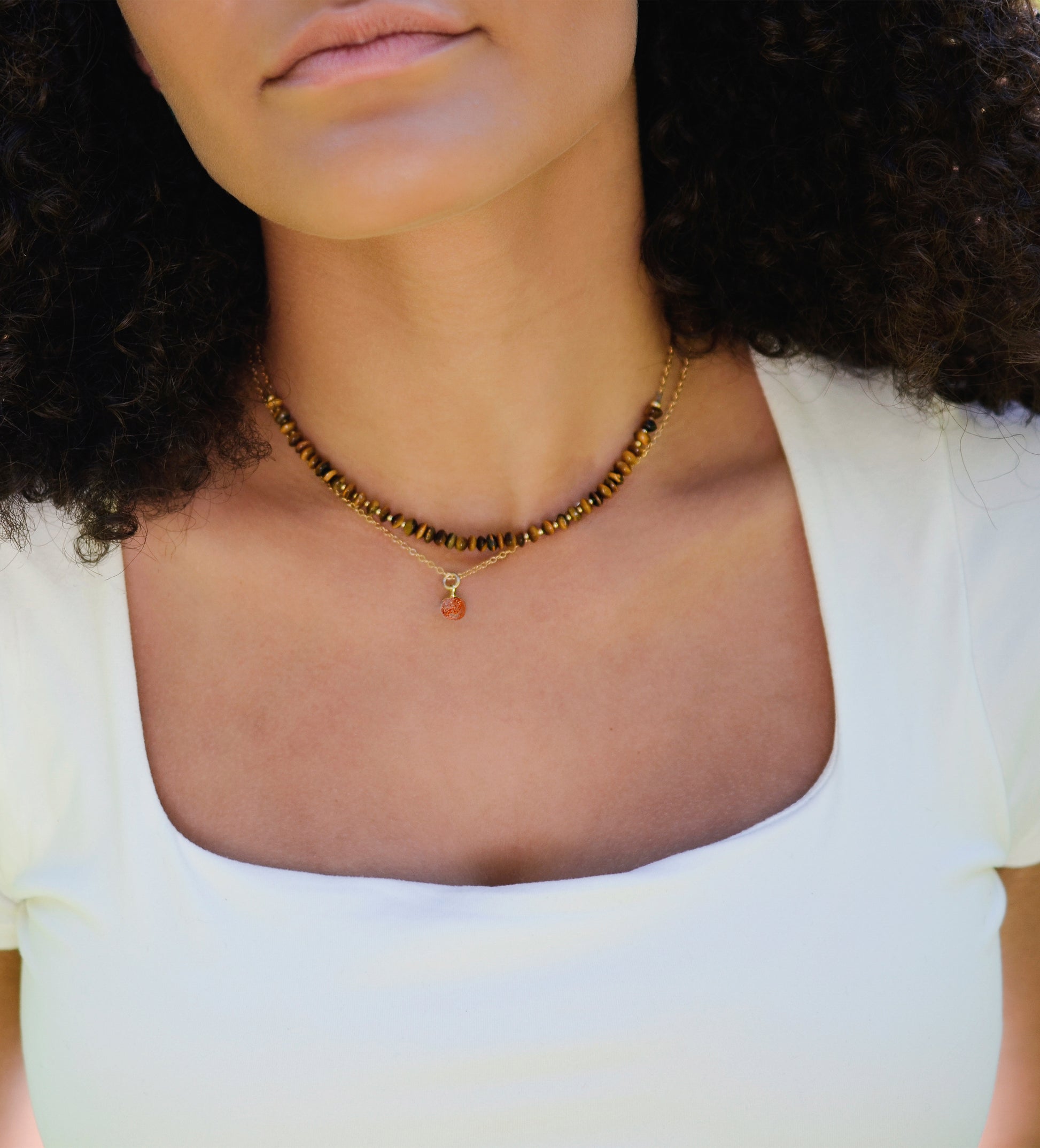 Natural orange Sunstone necklace. The stone is a faceted round and set onto a 14k gold filled chain. Modeled image.