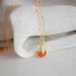 Natural orange Sunstone necklace. The stone is a faceted round and set onto a 14k gold filled chain.