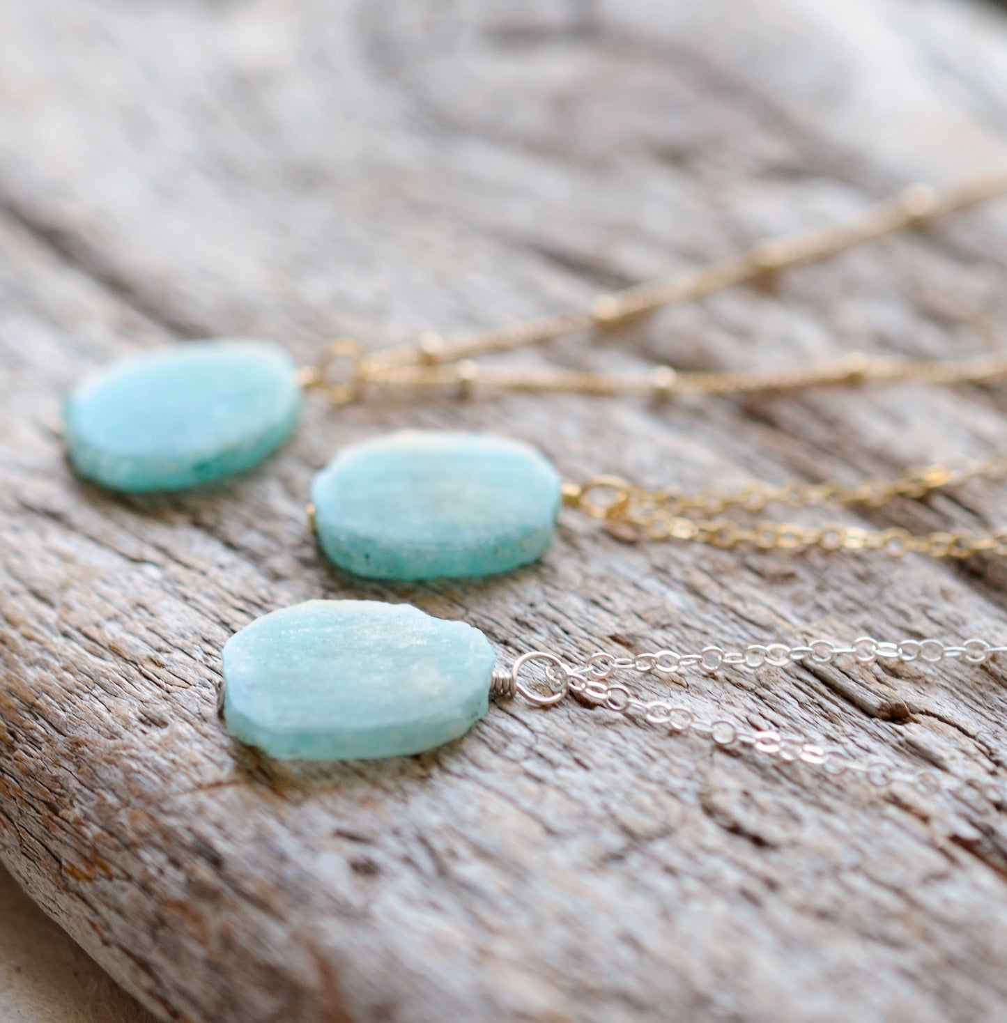 Aqua blue amazonite slice gemstone set onto a sterling silver or 14k gold filled chains. The stone is semi oval in shape, but irregular. It's smooth polished, but with raw edges.
