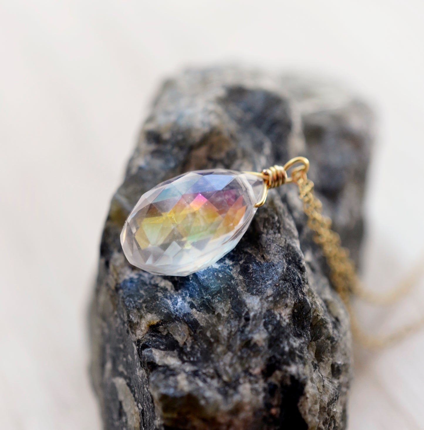 Close up image of the rainbow colors within the Mystic Topaz. The gemstone is a faceted teardrop shape. The 14k gold filled style is shown.