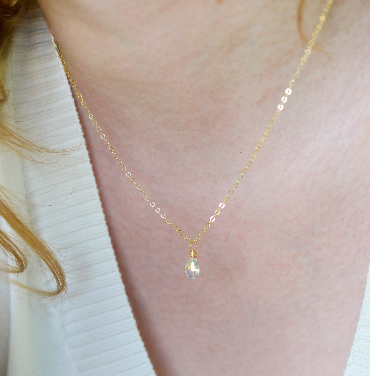 Rainbow Quartz teardrop crystal on a gold filled chain. The stone flashes a shimmering array of rainbow colors. Modeled image.