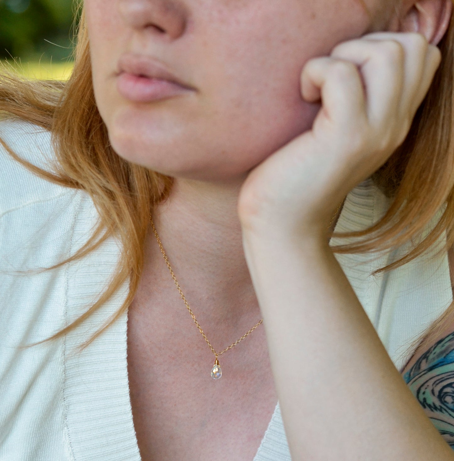 Rainbow Quartz teardrop crystal on a gold filled chain. The stone flashes a shimmering array of rainbow colors. Modeled image.