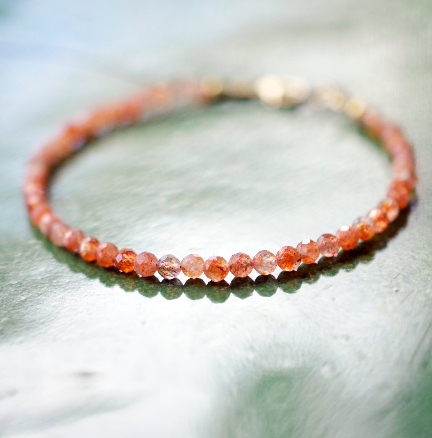 Dainty Sunstone beaded bracelet with orange to clear glittering gemstones. Clasp is sterling silver or gold filled.