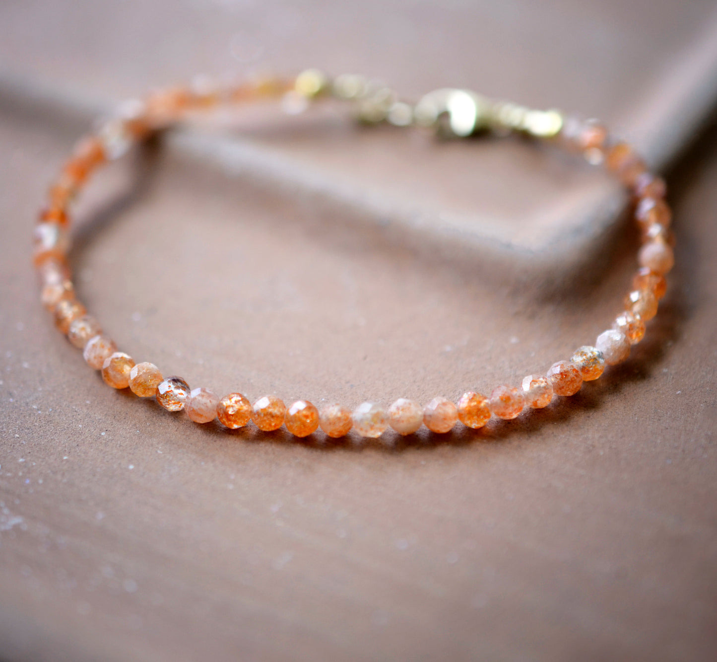 Dainty Sunstone beaded bracelet with orange to clear glittering gemstones. Clasp is sterling silver or gold filled.