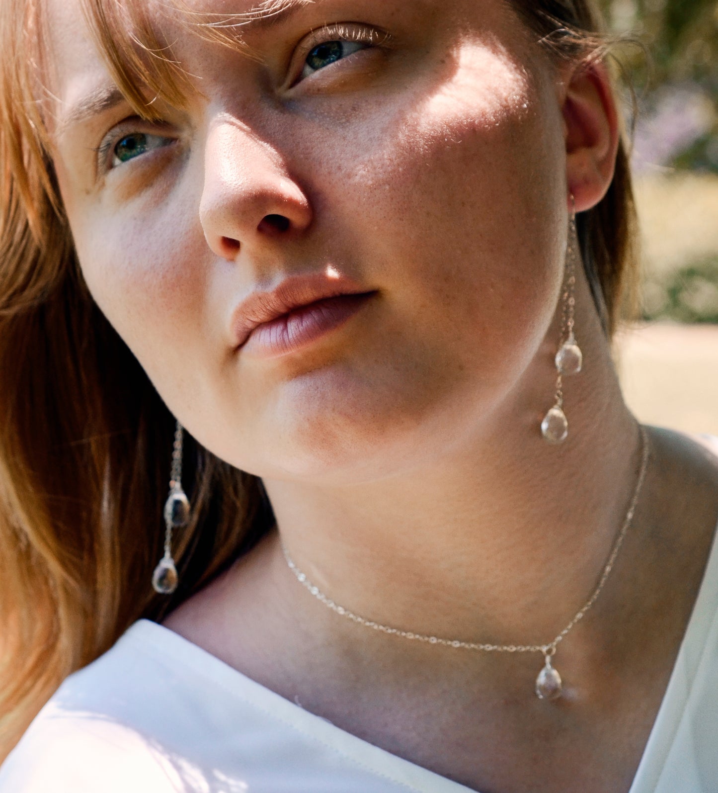 Long clear crystal quartz earrings with two teardrop dangles hanging from a dainty chain. Shown in sterling silver.