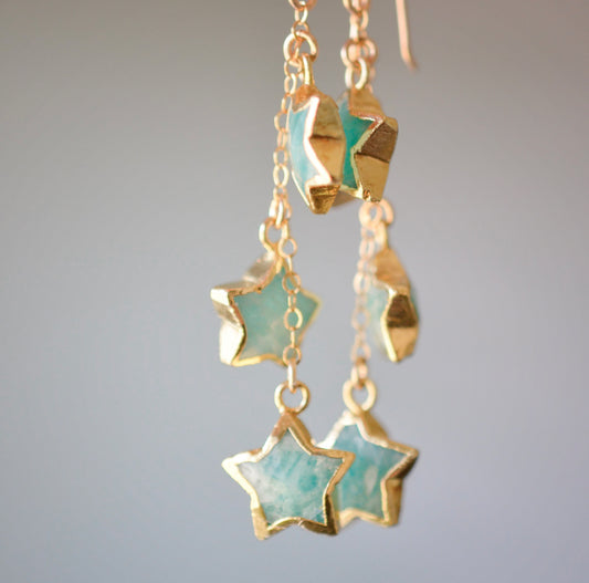 Close up of blue-green natural amazonite star shaped stones set on long dangles in gold.