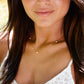Close-up of a woman wearing a gold necklace with a blurred background. This necklace is handmade with white natural pearls set onto a 14k gold filled or sterling silver chain.