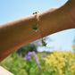 Gold bracelet with Amazonite gemstone star-shaped charms on a wrist against a blurred natural background.