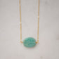 Aqua blue amazonite slice gemstone set onto a 14k gold filled chain. The stone is semi oval in shape, but irregular. It's smooth polished, but with raw edges.