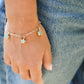 Gold bracelet with Amazonite gemstone star charms on a wrist against a denim background.