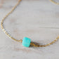 Genuine aqua blue Amazonite gemstone cut into a faceted cube and suspended on a gold filled cable chain. Close Up.