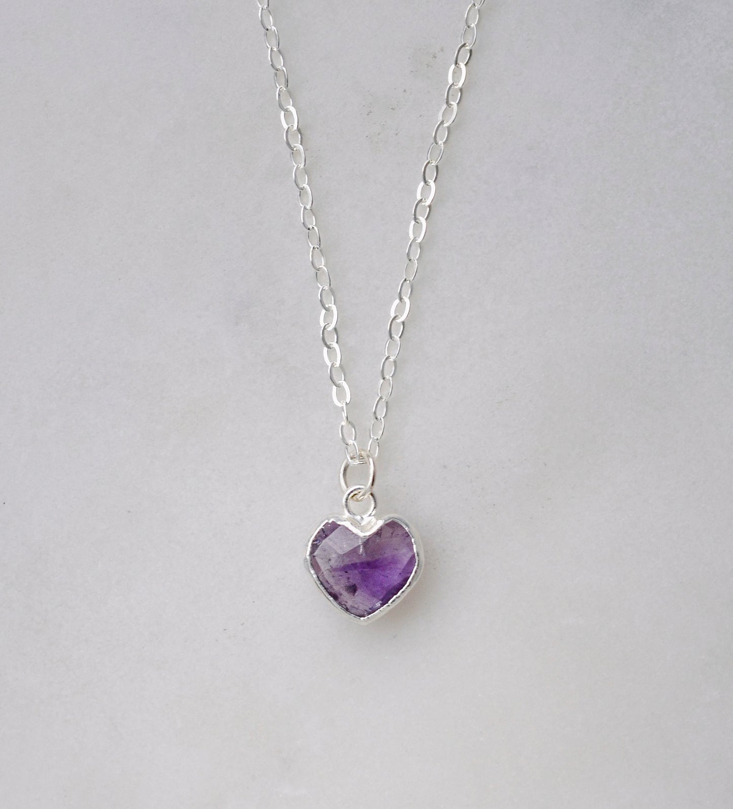 Purple heart shaped Amethyst pendant suspended from a sterling silver chain. 