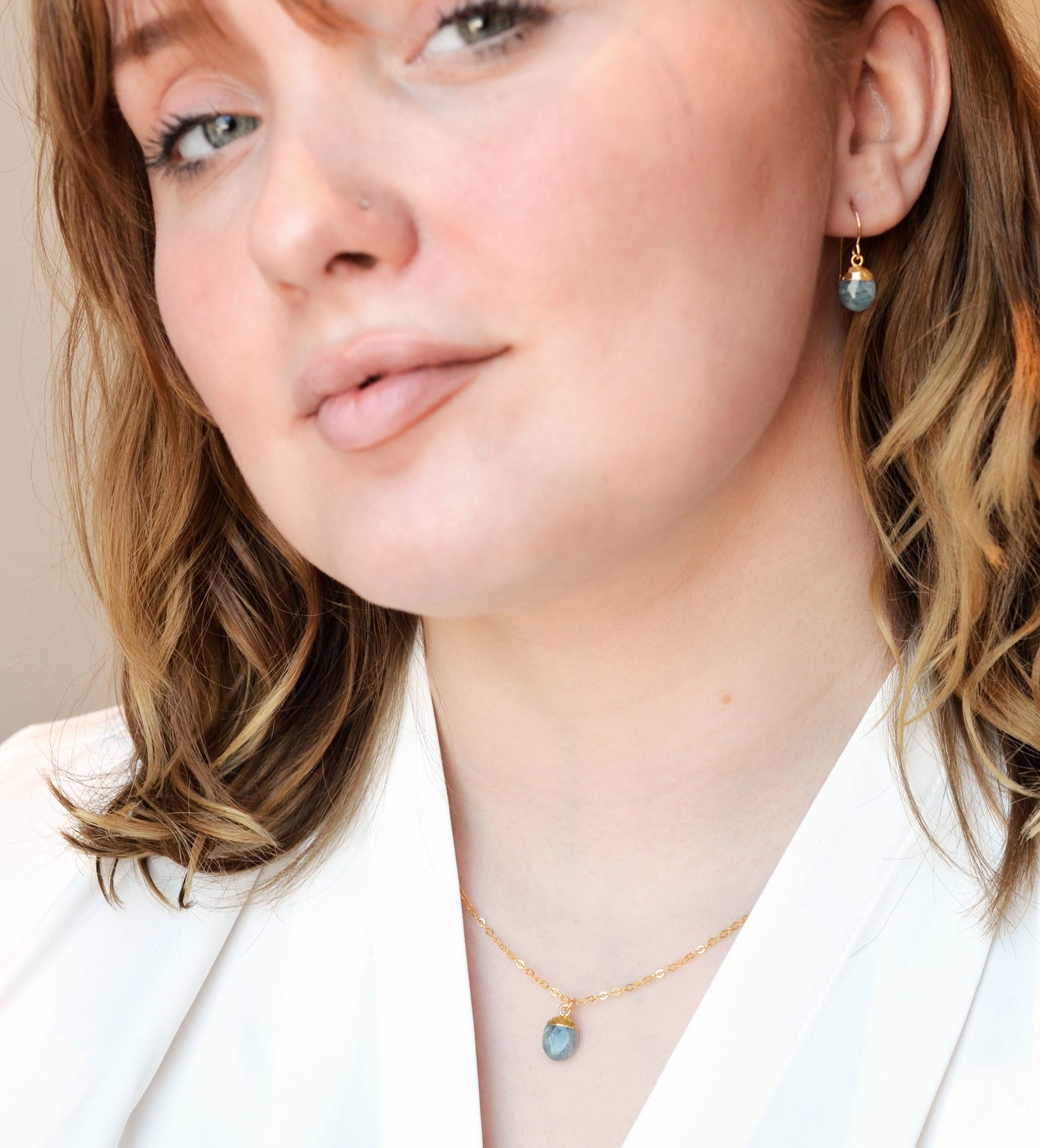 A woman wearing a matching genuine blue aquamarine crystal necklace and earring set. Handmade minimalist stone jewelry by Gemnia.