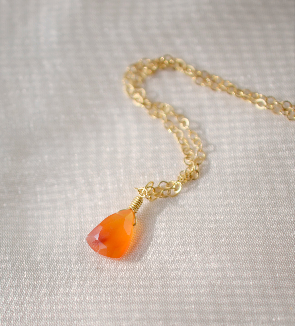 A natural orange to orange-red faceted Carnelian teardrop set on a 14k gold filled chain. The stone is real and a triangular teardrop shape. Handmade in Connecticut by Gemnia, this necklace is also available in sterling silver. 