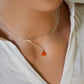 Natural orange Carnelian teardrop gemstone set onto a sterling silver chain. Modeled image.