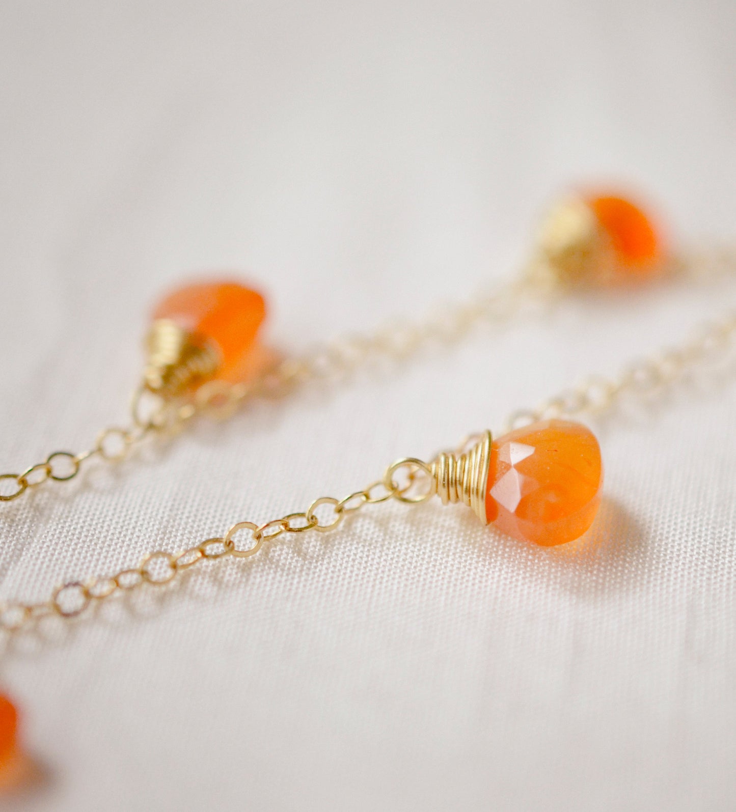 Handmade necklace featuring nine natural Carnelian gemstones set onto a gold filled chain. Sterling Silver is also available. Close up image.