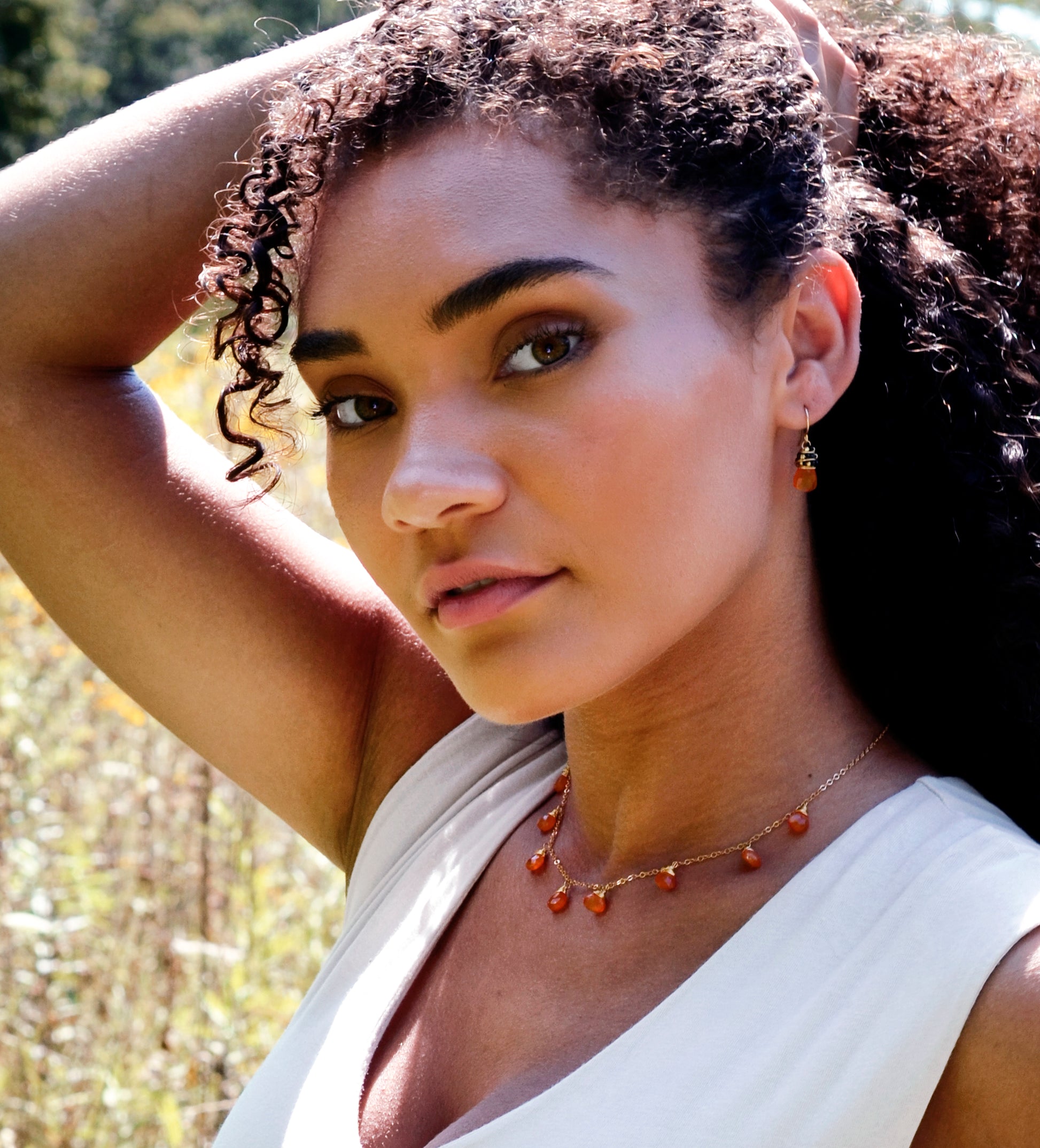 Handmade necklace featuring nine natural Carnelian gemstones set onto a gold filled chain. Sterling Silver is also available. Modeled Image.