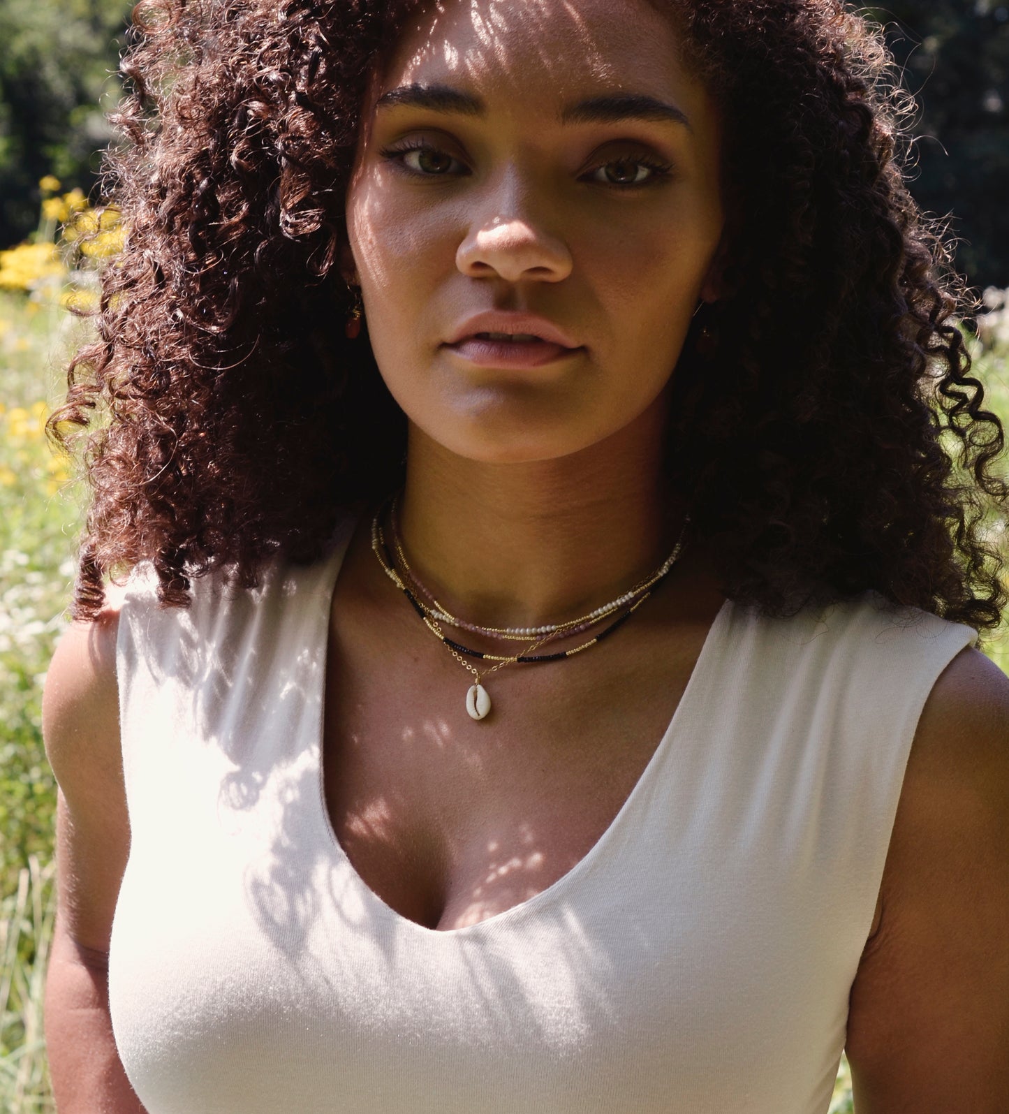 Creamy white natural Cowrie shell set onto a 14k gold filled chain. Modeled image.