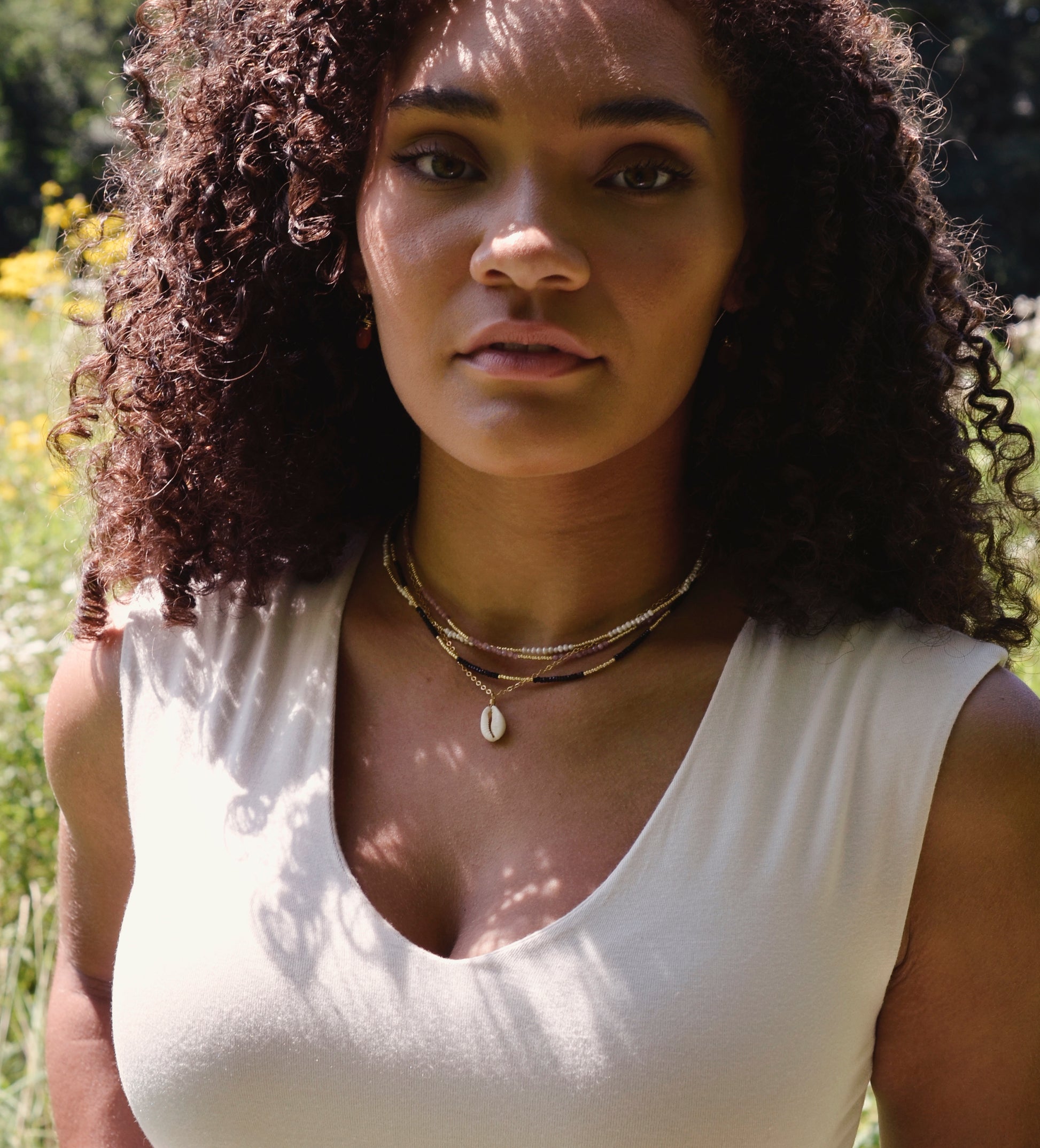 Creamy white natural Cowrie shell set onto a 14k gold filled chain. Modeled image.