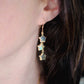 A woman wearing long labradorite earrings with three gemstone stars set in gold. These celestial dangles are handmade in gold or sterling silver by Gemnia in New England.