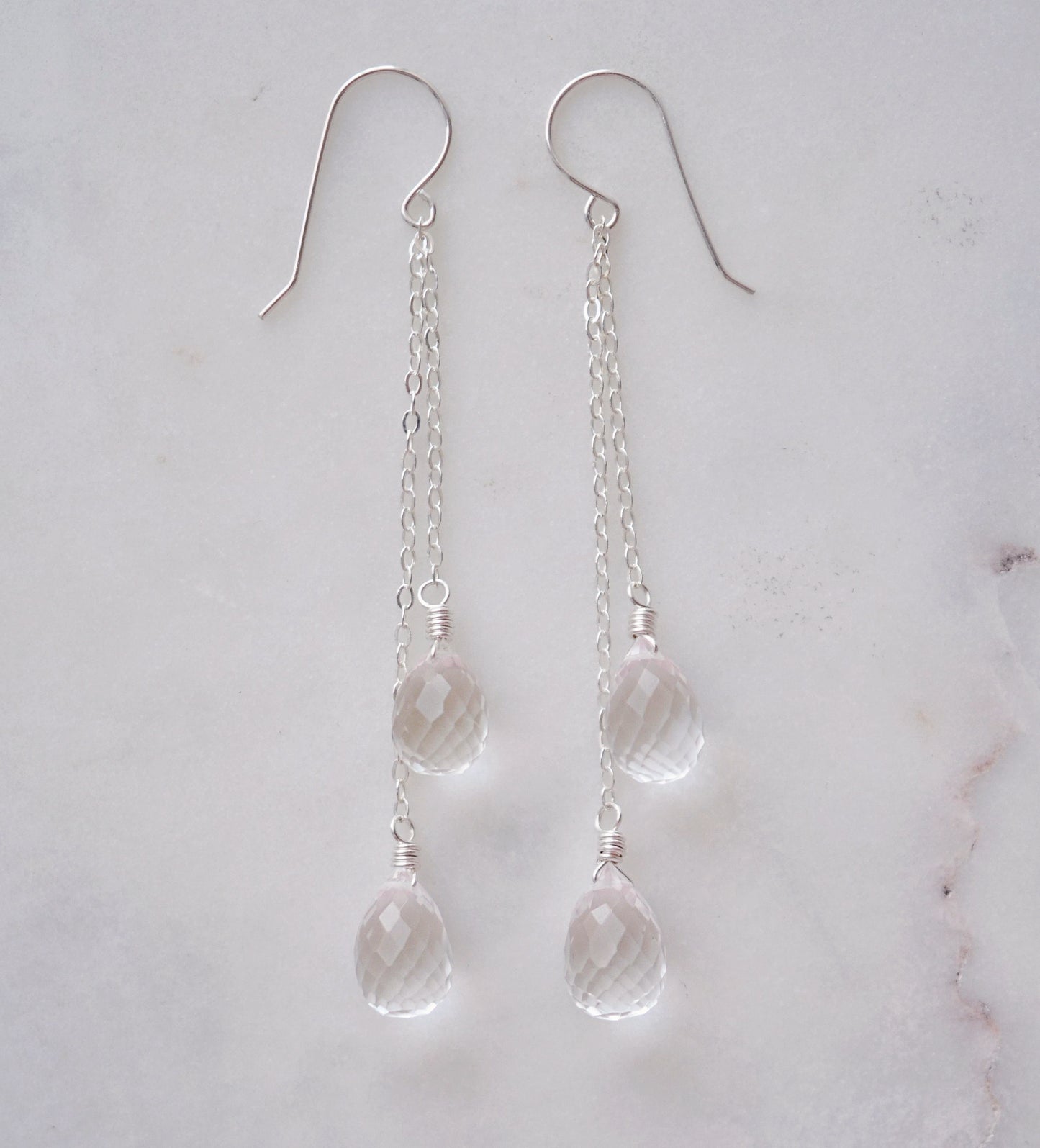 Long clear crystal quartz earrings with two teardrop dangles hanging from a dainty sterling silver chain.