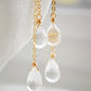 Long clear crystal quartz earrings with two teardrop dangles hanging from a dainty 14k gold filled chain. Close up of gemstones.