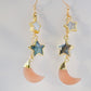 Mother of pearl, Labradorite, and Peach Moonstone moon and star dangle earrings in gold. Each earring has two stars hanging over a peach moonstone crescent.