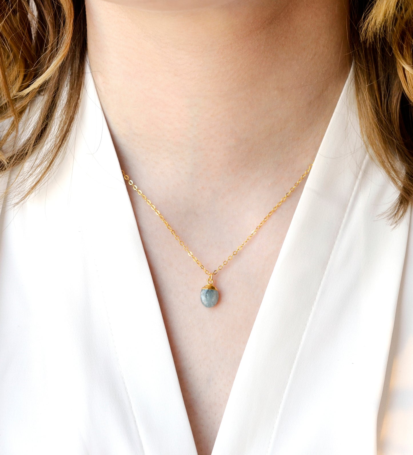 Modeled image of a woman wearing a dainty gold aquamarine pendant necklace. Handcrafted in Connecticut by GEMNIA.