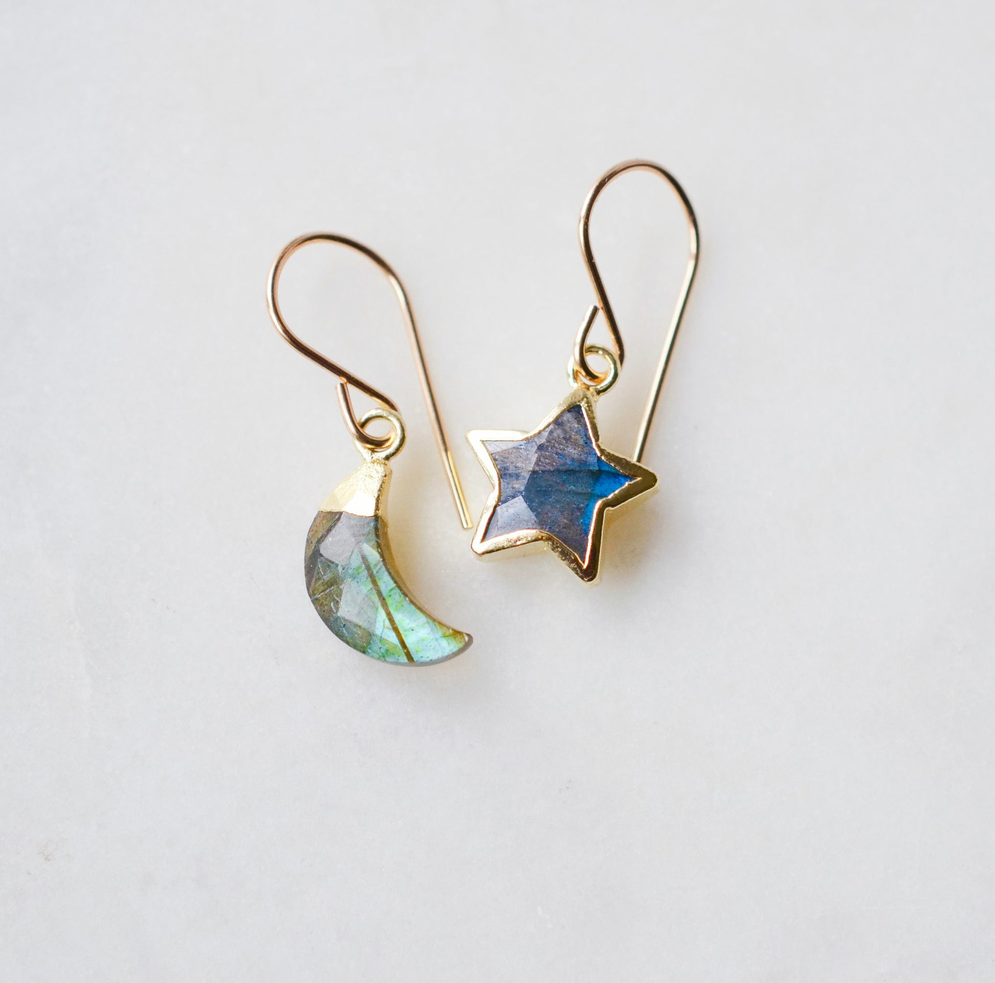 Labradorite Moon and Star earrings. One dangle is a faceted crescent moon, while the other is a star. The stones are naturally gray in color, but shift blue or green with movement. Available in gold or silver.