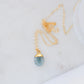 A handmade crystal necklace with a blue aquamarine teardrop pendant on a minimalist 14k gold filled chain. 