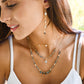 A woman wearing three layered necklaces of labradorite, pearls, and starts. Handmade celestial jewelry style by Gemnia.