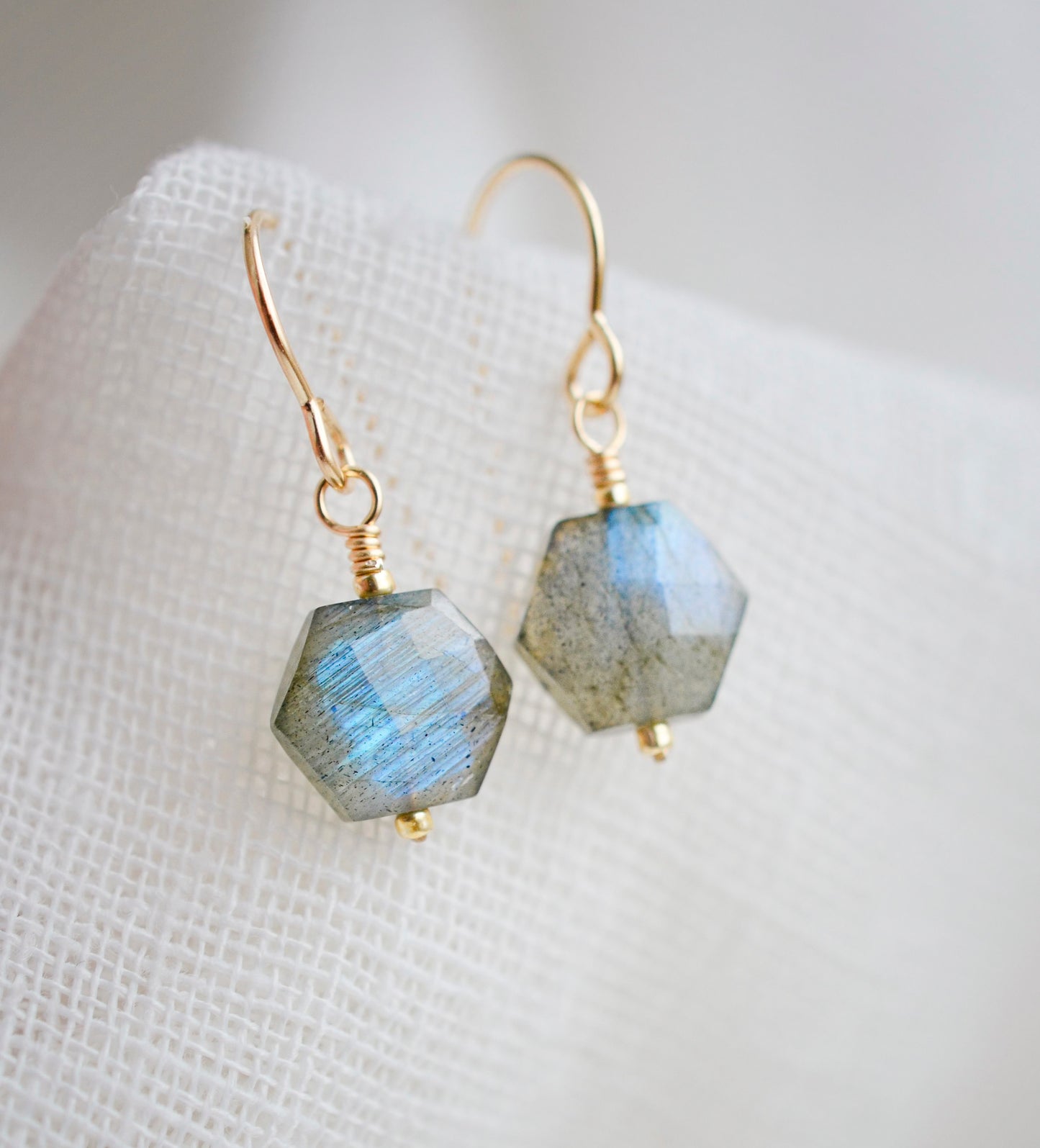 Blue flashing Labradorite gemstones in a faceted hexagonal shape dangle from 14k gold filled earring hooks. Small gold beads accent below the stone. Also available in sterling silver.