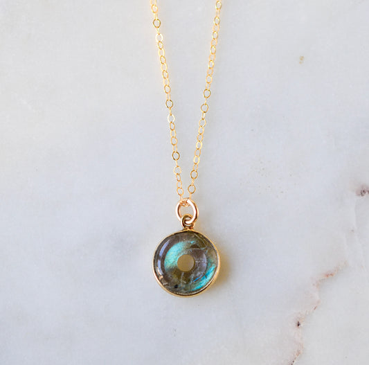 A doughnut shaped natural labradorite round pendant set in gold. The dainty chain is 14k gold filled. The jewelry is handmade in Connecticut by GEMNIA.