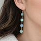 A closeup of a woman wearing long labradorite dangle earrings with hexagon shaped gemstones in 14k gold filled. Handmade in Connecticut by Gemnia.