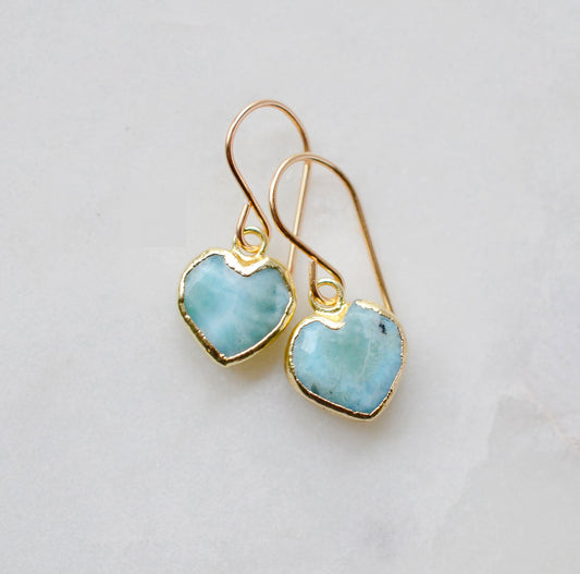 Aqua blue, natural Larimar stone heart earrings in gold. The stones range in blue, white, or green with the occasion mark of brown or black.