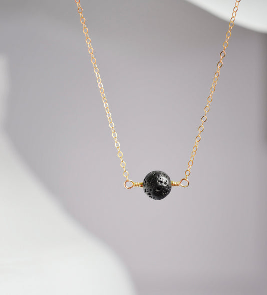 A round black lava stone suspended from a 14k gold filled chain.