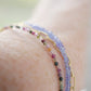 Tiny mulit-color Tourmaline faceted round gemstones on a gold beaded bracelet. Modeled image.