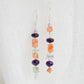 Mismatched gemstone long bar earrings shown in sterling silver. Stones include: amethyst, aquamarine, fluorite, and sunstone. Stones are set onto a long straight bar.