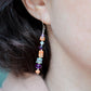 Mismatched gemstone long bar earrings shown in sterling silver. Stones include: amethyst, aquamarine, fluorite, and sunstone. Stones are set onto a long straight bar. Modeled image.