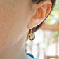 Smooth polished flat circle moss agate earrings shown in gold filled. Modeled image.