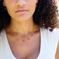 Handmade necklace featuring nine natural Carnelian gemstones set onto a gold filled chain. Sterling Silver is also available. Modeled Image.
